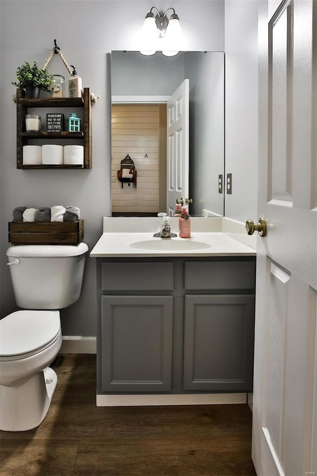 bathroom with toilet, baseboards, wood finished floors, and vanity