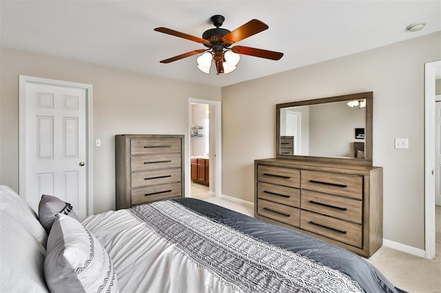 bedroom with baseboards, ensuite bathroom, a ceiling fan, and light colored carpet