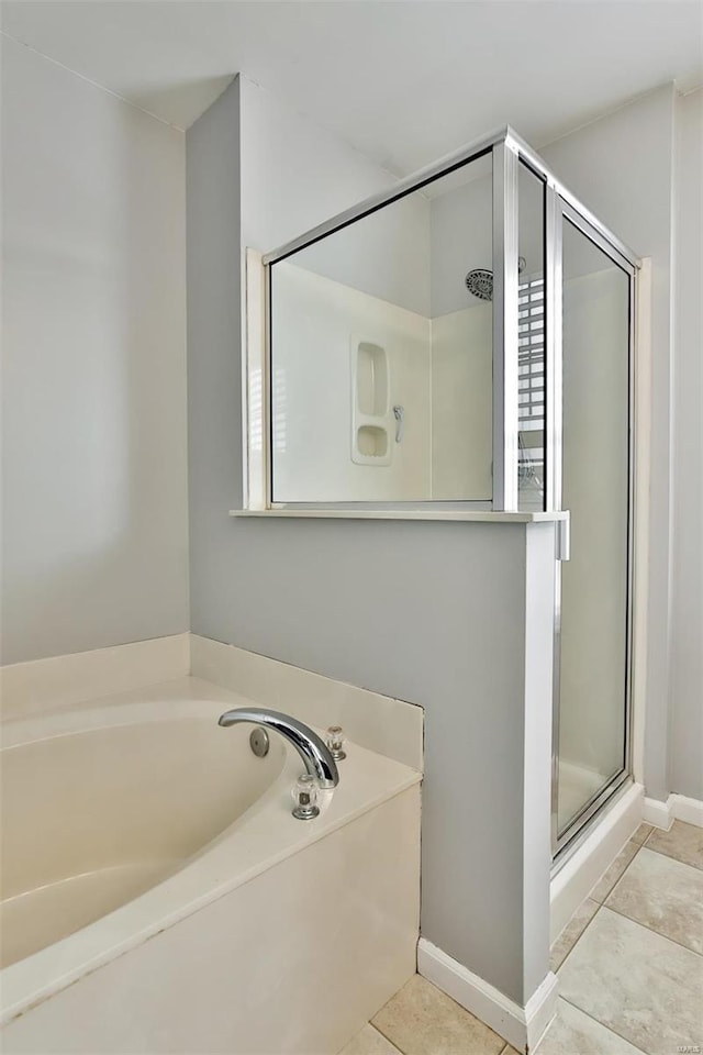 full bathroom with a stall shower, baseboards, a bath, and tile patterned floors