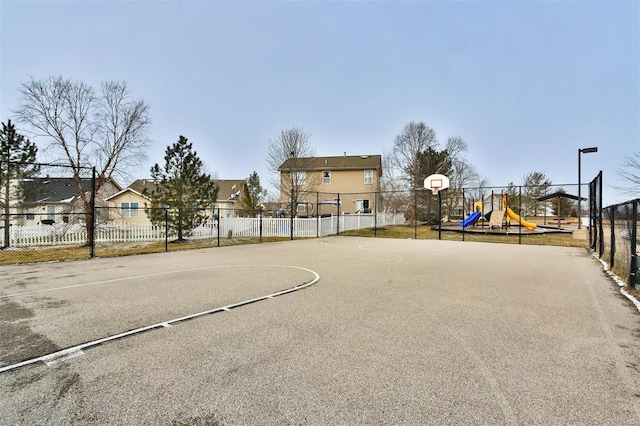 view of basketball court featuring community basketball court, fence, playground community, and a residential view