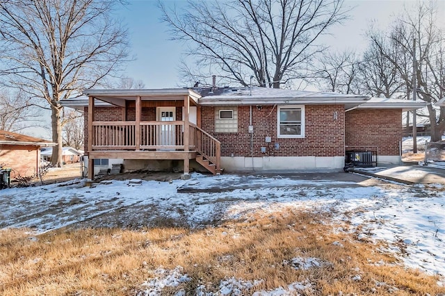 snow covered house with central AC and covered porch