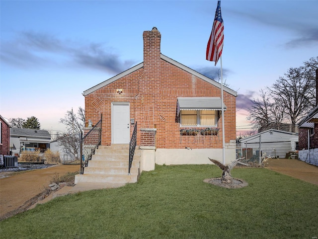 bungalow-style house with cooling unit and a lawn