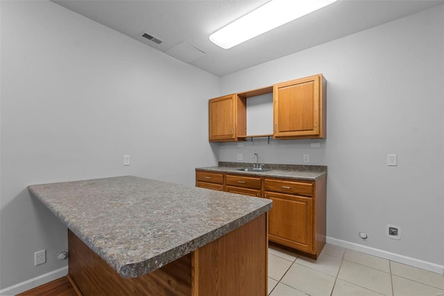 kitchen with sink, a breakfast bar area, light tile patterned floors, and kitchen peninsula