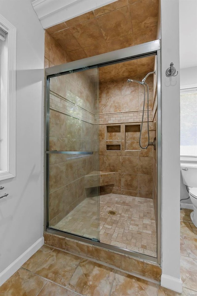 bathroom with a shower with shower door and toilet