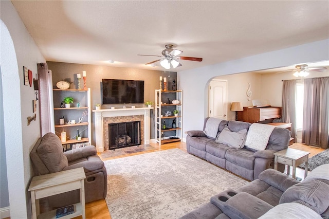 living room with ceiling fan, a high end fireplace, and light hardwood / wood-style floors