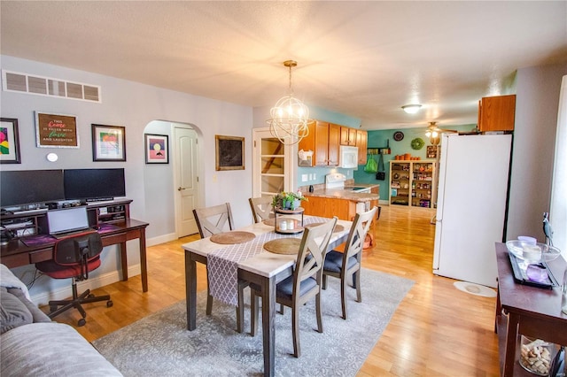 dining room featuring ceiling fan with notable chandelier and light hardwood / wood-style floors