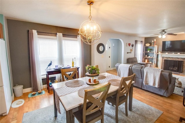 dining space with ceiling fan with notable chandelier, a wealth of natural light, and light wood-type flooring