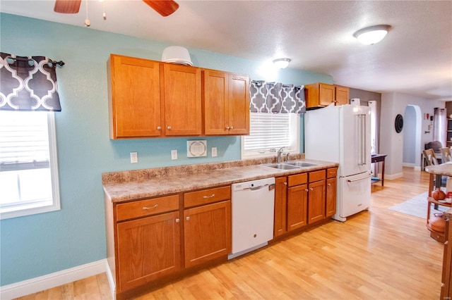 kitchen with ceiling fan, white appliances, sink, and light hardwood / wood-style flooring