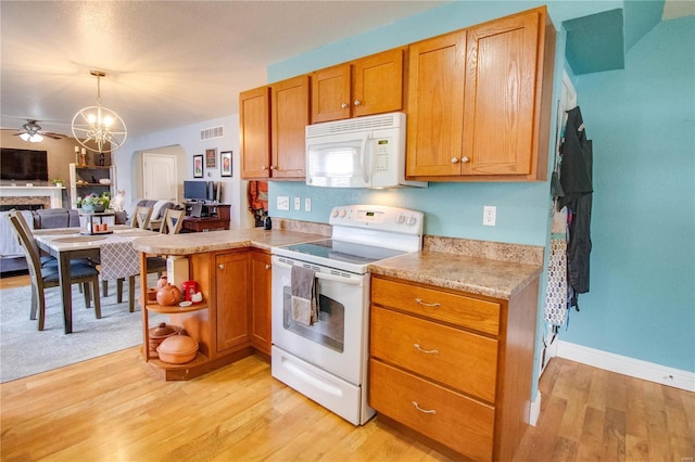 kitchen with white appliances, ceiling fan with notable chandelier, decorative light fixtures, kitchen peninsula, and light wood-type flooring