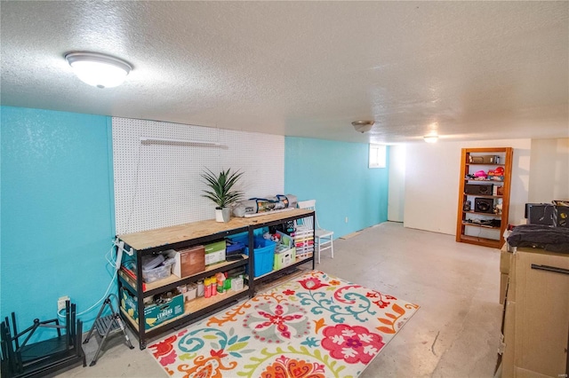 playroom featuring concrete floors and a textured ceiling