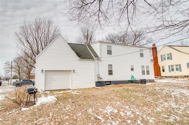 snow covered house featuring a garage and central air condition unit