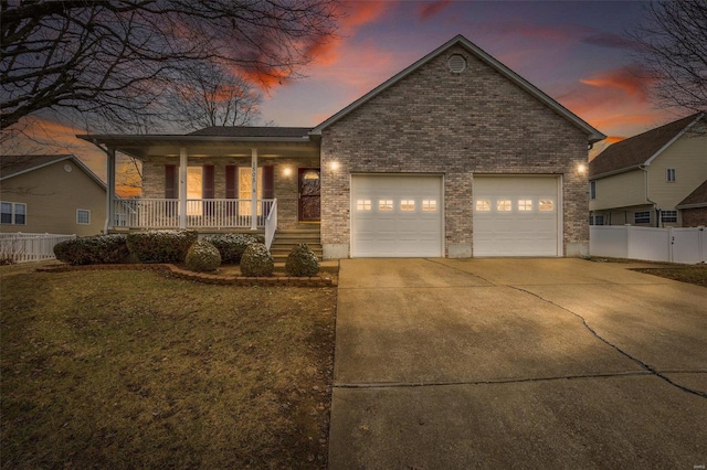 view of front of property featuring a garage, a lawn, and covered porch