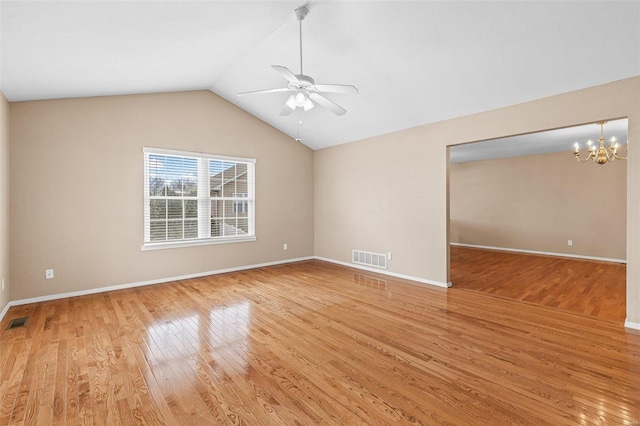 empty room featuring ceiling fan with notable chandelier, vaulted ceiling, and light wood-type flooring