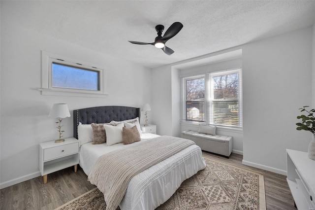 bedroom with a textured ceiling, baseboards, and wood finished floors