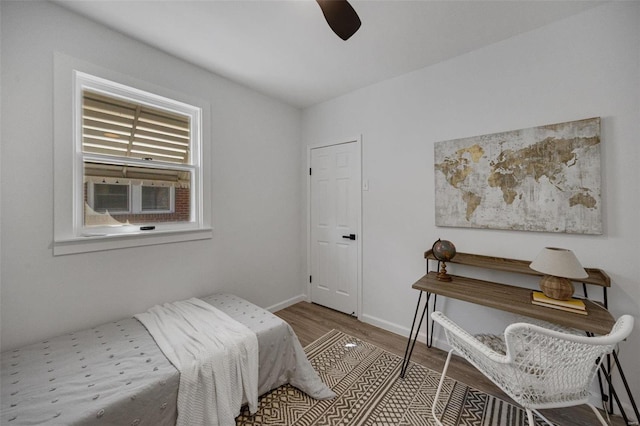 bedroom with a ceiling fan, cooling unit, baseboards, and wood finished floors