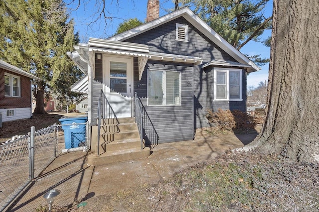 bungalow-style house featuring entry steps, a chimney, and fence