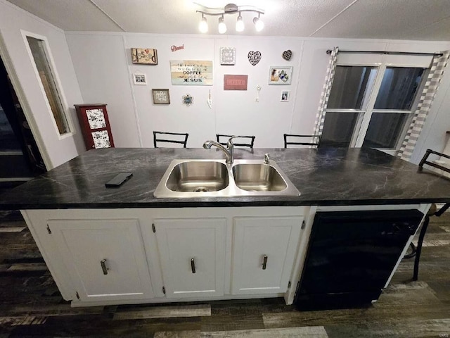 kitchen featuring white cabinetry, sink, dishwashing machine, dark wood-type flooring, and a center island with sink