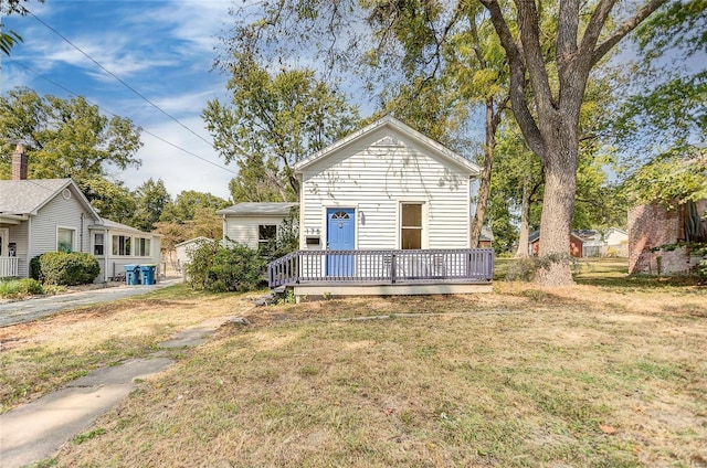 bungalow-style home featuring a front yard and a deck