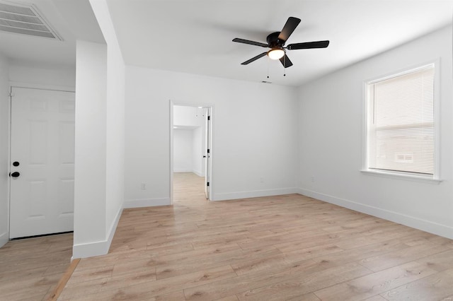 unfurnished room featuring light wood finished floors, a ceiling fan, visible vents, and baseboards