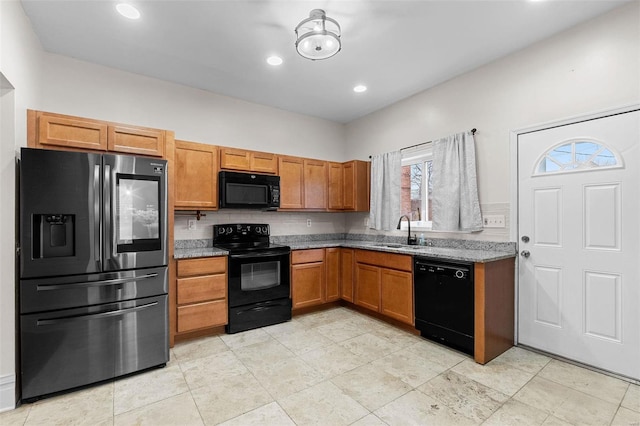 kitchen featuring light stone counters, sink, decorative backsplash, and black appliances