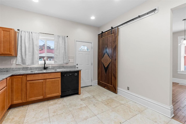 kitchen with a wealth of natural light, light stone countertops, black dishwasher, and sink