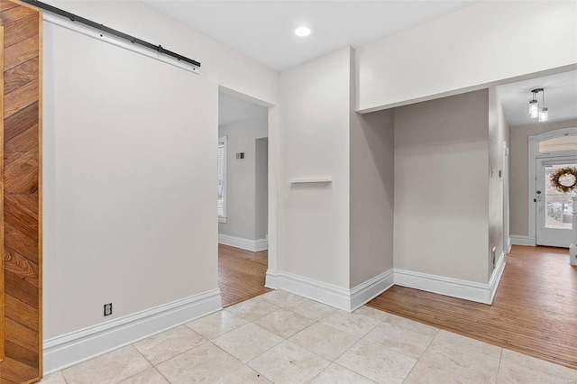 hallway with a barn door and light tile patterned flooring