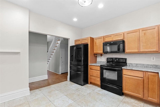 kitchen with light tile patterned floors, decorative backsplash, light stone counters, and black appliances