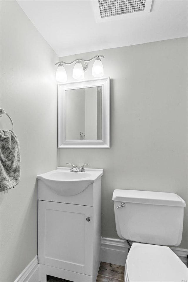 bathroom with hardwood / wood-style flooring, vanity, and toilet