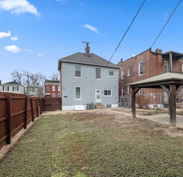 back of property with a yard, a gazebo, and central AC