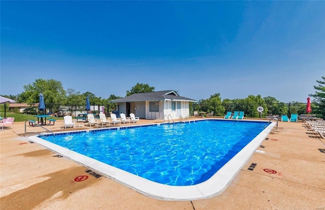 pool with an outbuilding, a patio, and fence