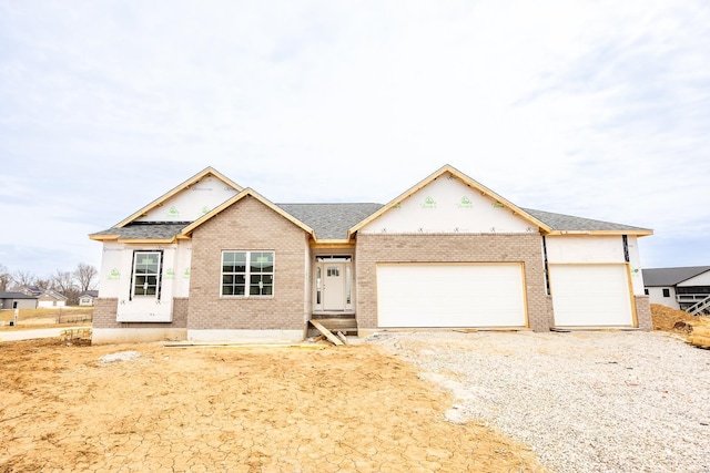 view of front of home with a garage, driveway, brick siding, and roof with shingles