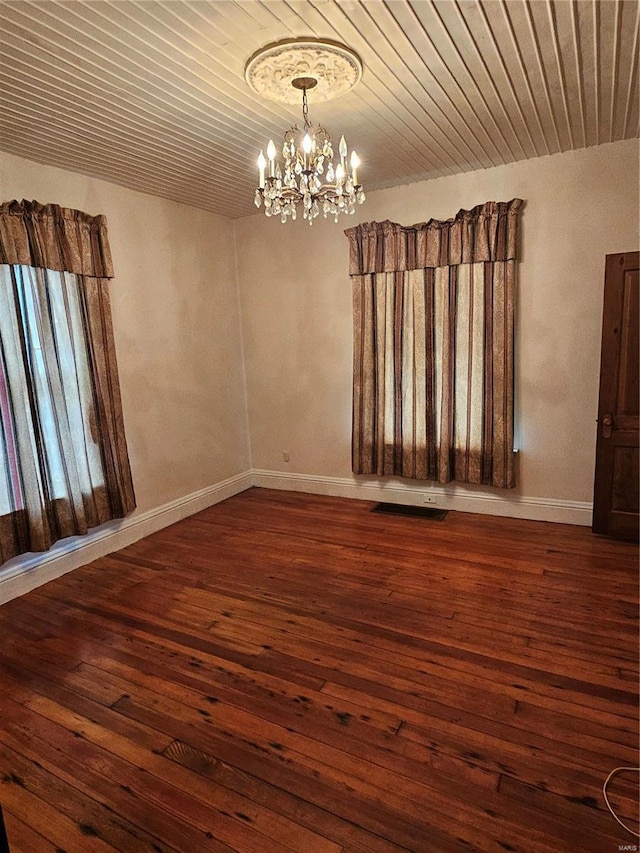 spare room with dark hardwood / wood-style floors, wood ceiling, and a chandelier