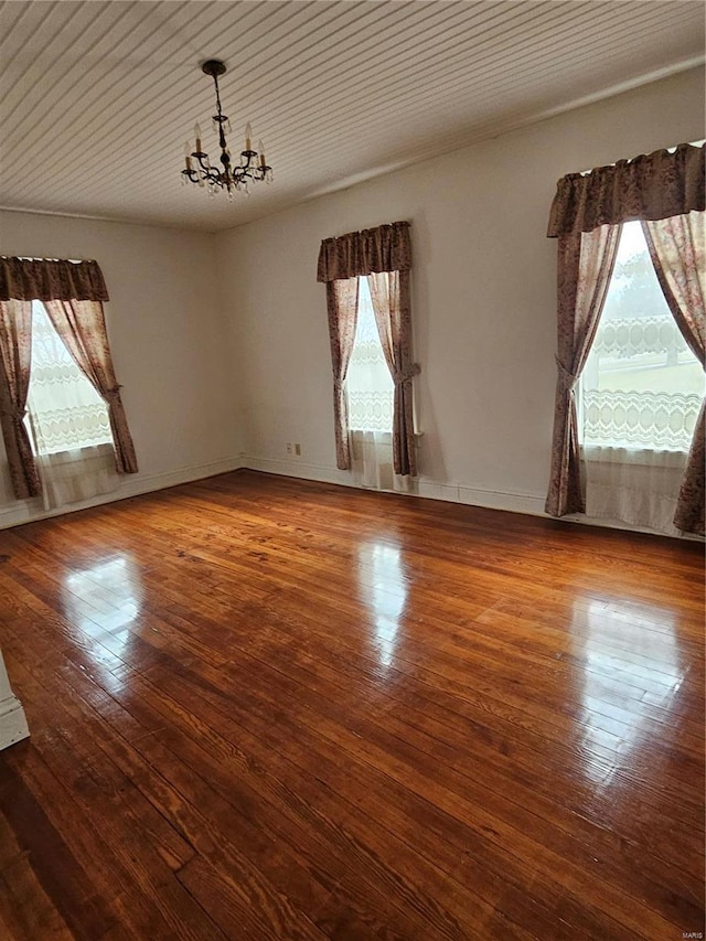 spare room featuring hardwood / wood-style floors and a notable chandelier