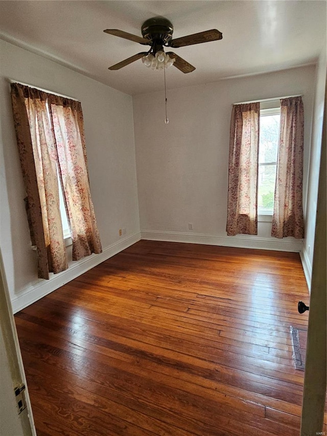 empty room with ceiling fan and dark hardwood / wood-style flooring