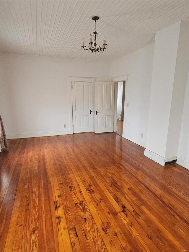 empty room featuring an inviting chandelier and wood-type flooring