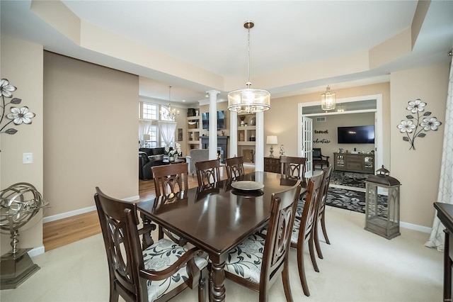 dining space with a raised ceiling, decorative columns, baseboards, and an inviting chandelier