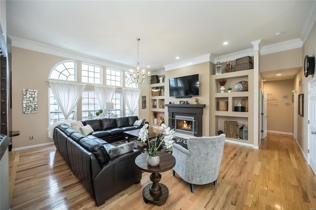 living room featuring a warm lit fireplace, light wood finished floors, ornamental molding, and built in features