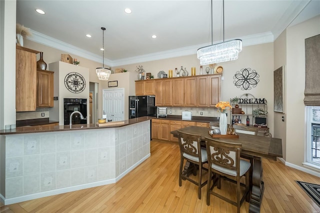 kitchen with brown cabinetry, dark countertops, decorative light fixtures, and black appliances