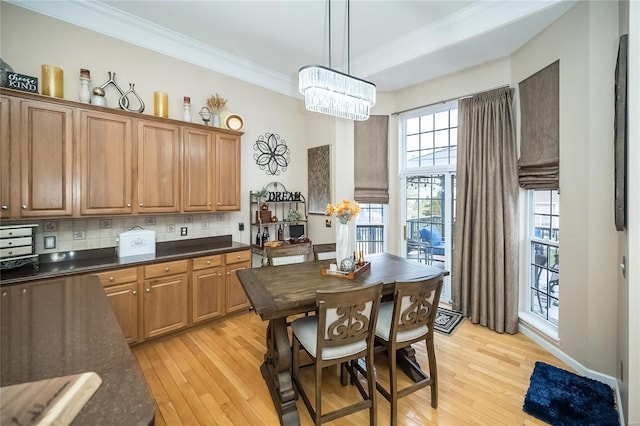 kitchen with light wood-type flooring, dark countertops, decorative light fixtures, and decorative backsplash