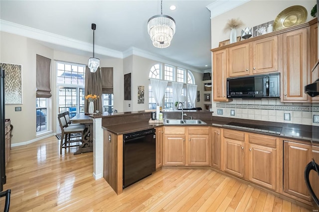 kitchen featuring decorative light fixtures, dark countertops, ornamental molding, a sink, and black appliances