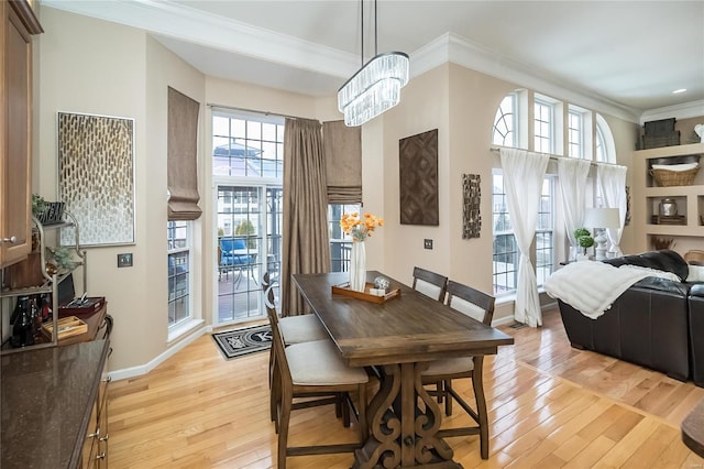 dining room featuring crown molding, light wood-style flooring, baseboards, and an inviting chandelier