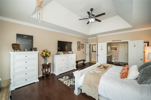 bedroom with crown molding, a tray ceiling, dark wood-style flooring, and ensuite bathroom