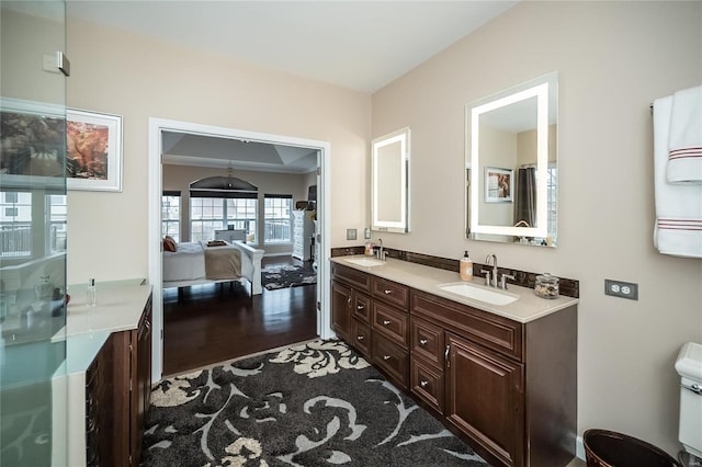 full bath with ensuite bathroom, double vanity, wood finished floors, and a sink