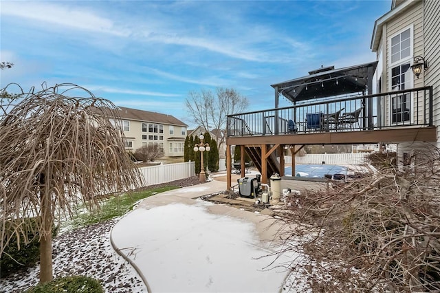 yard covered in snow featuring fence and a wooden deck