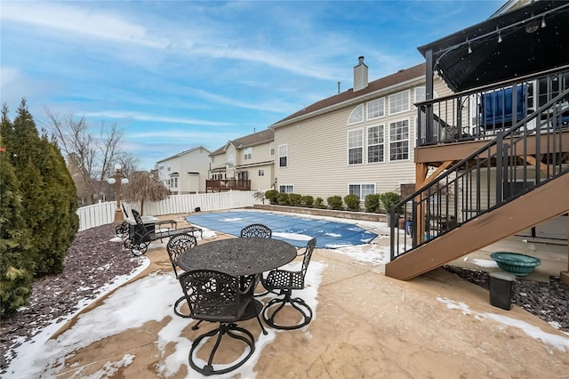 snow covered pool featuring stairway, a patio area, and fence