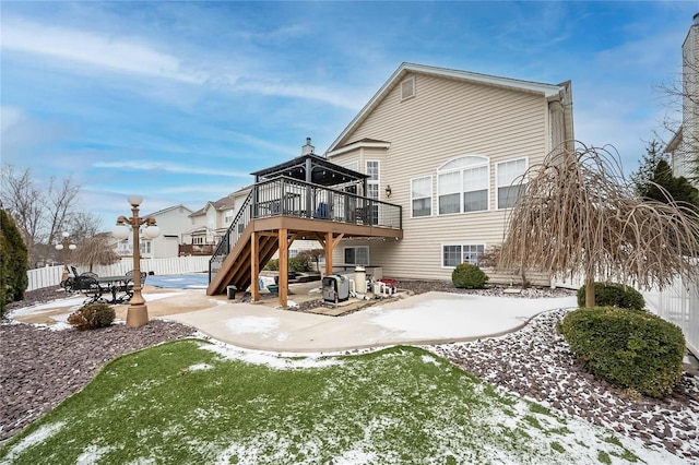 snow covered house with stairs, a patio area, fence, and a wooden deck