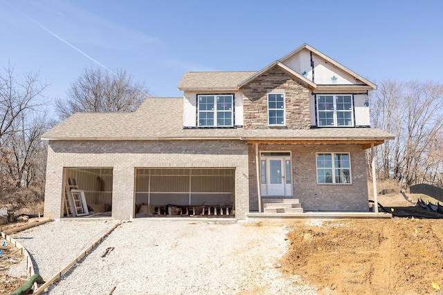 view of front of home with stone siding, brick siding, and gravel driveway