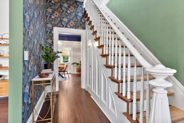stairs with baseboards, wallpapered walls, and wood finished floors
