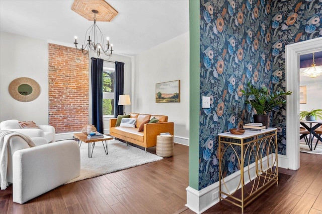 living room with a notable chandelier, an accent wall, hardwood / wood-style floors, baseboards, and wallpapered walls