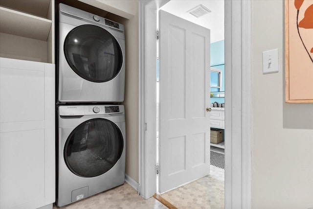 laundry room with laundry area, visible vents, stacked washing maching and dryer, baseboards, and light floors